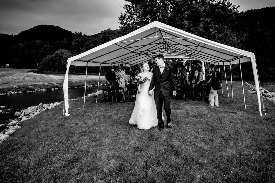 A bride and groom standing under a tent.