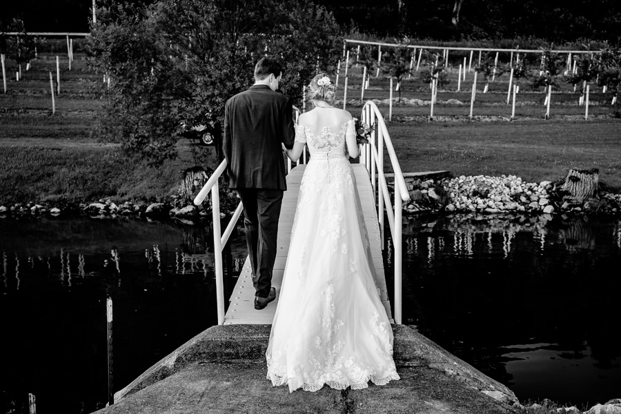 A bride and groom standing on a dock in black and white.