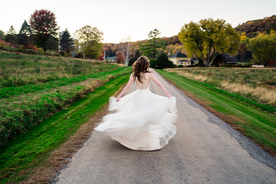 A bride walks down a country road in her wedding dress.