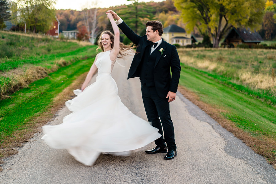 A bride and groom dancing on a country road.
