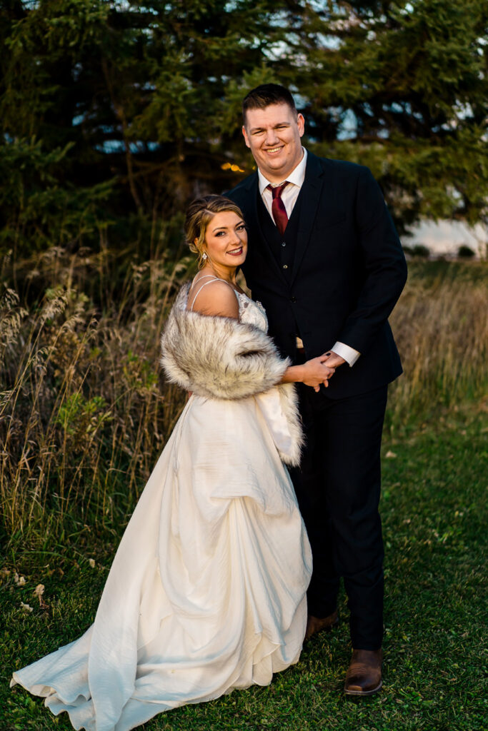 A bride and groom posing for a photo in a field.