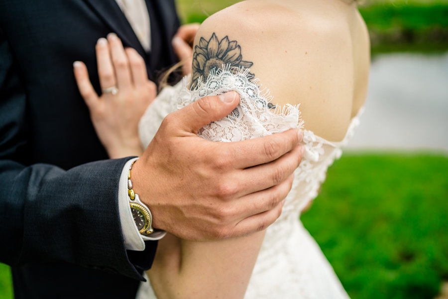 A bride and groom with tattoos on their arms.