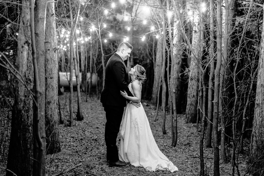 Black and white photo of a bride and groom kissing in the woods.