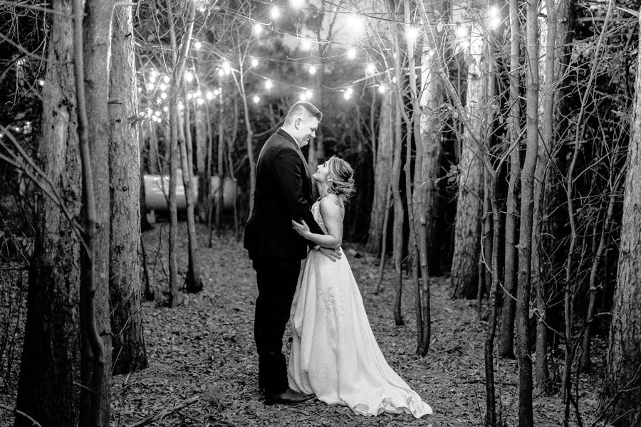 Black and white photo of a bride and groom kissing in the woods.