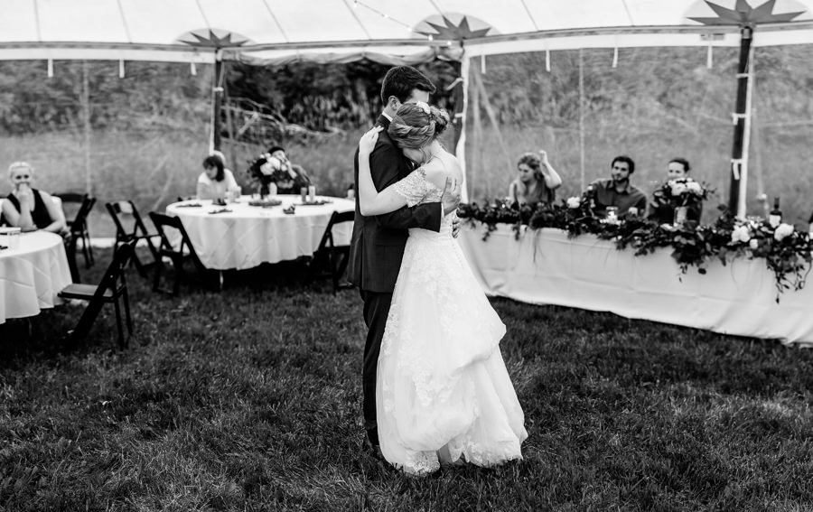 A bride and groom sharing a first dance in a tent.