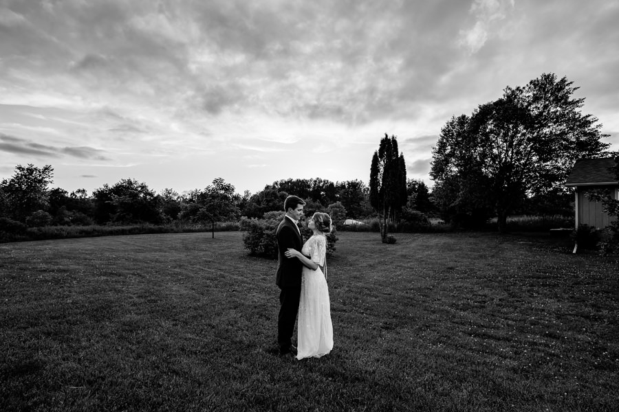A black and white photo of a bride and groom in a field.