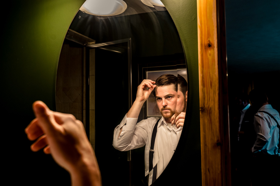 A man is putting on a tie in front of a mirror.