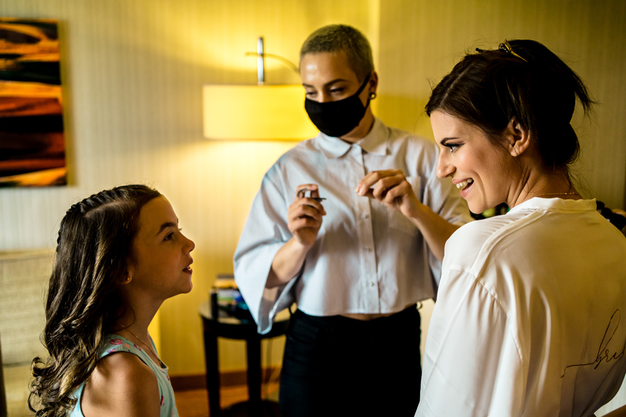 A woman is getting her daughter's makeup done in a hotel room.