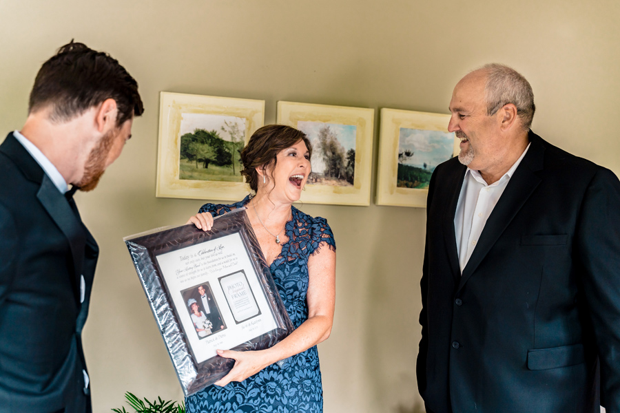A man in a suit and a woman holding a framed picture.