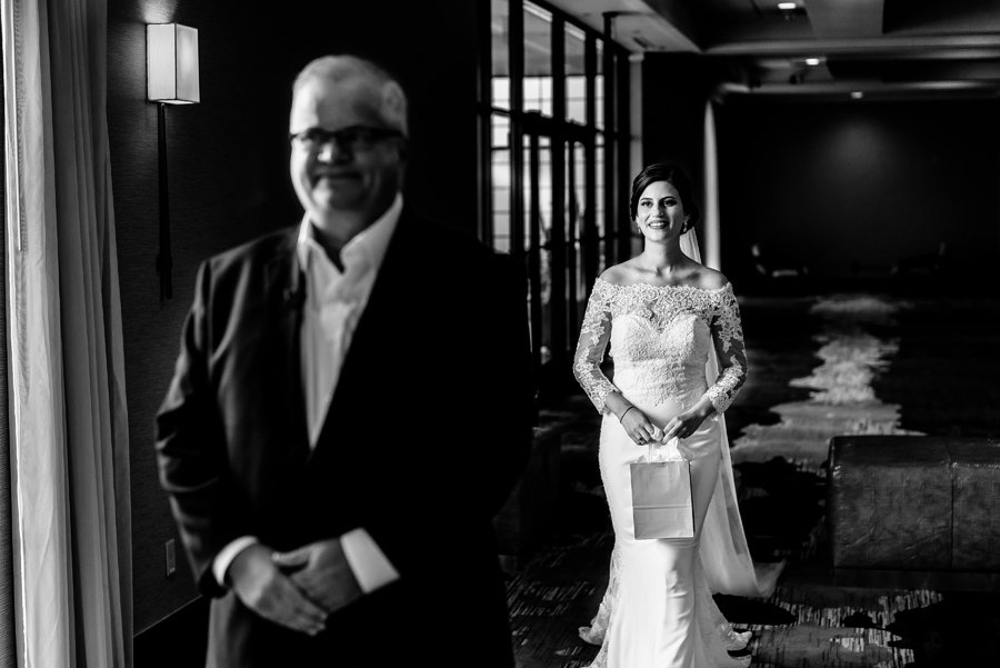 A bride and her father standing in a hallway.