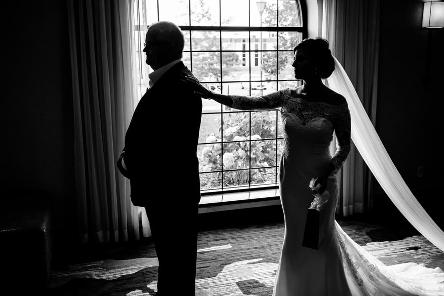 A bride and groom standing in front of a window.