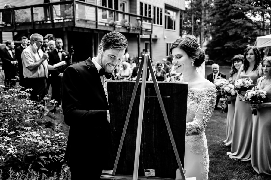 A bride and groom writing their wedding vows on an easel.