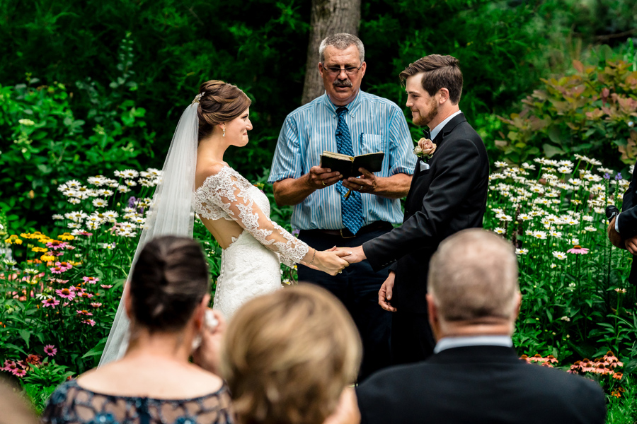 A bride and groom exchange vows in a garden.