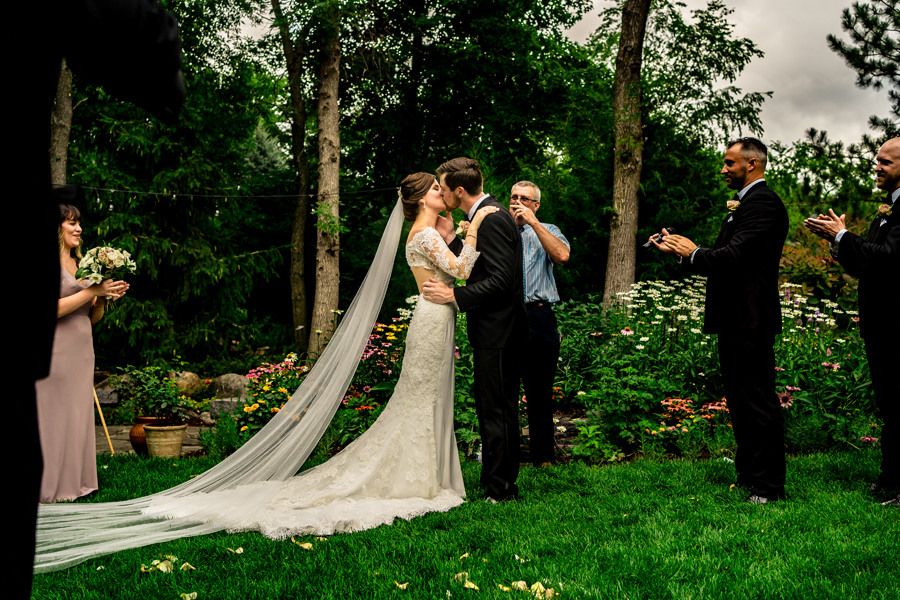 A bride and groom kissing in the grass.