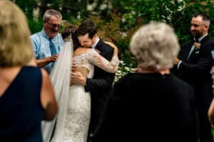 A bride and groom hugging during their wedding ceremony.