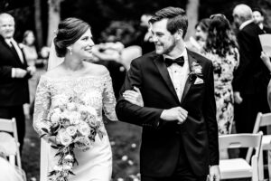 Black and white photo of a bride and groom walking down the aisle.