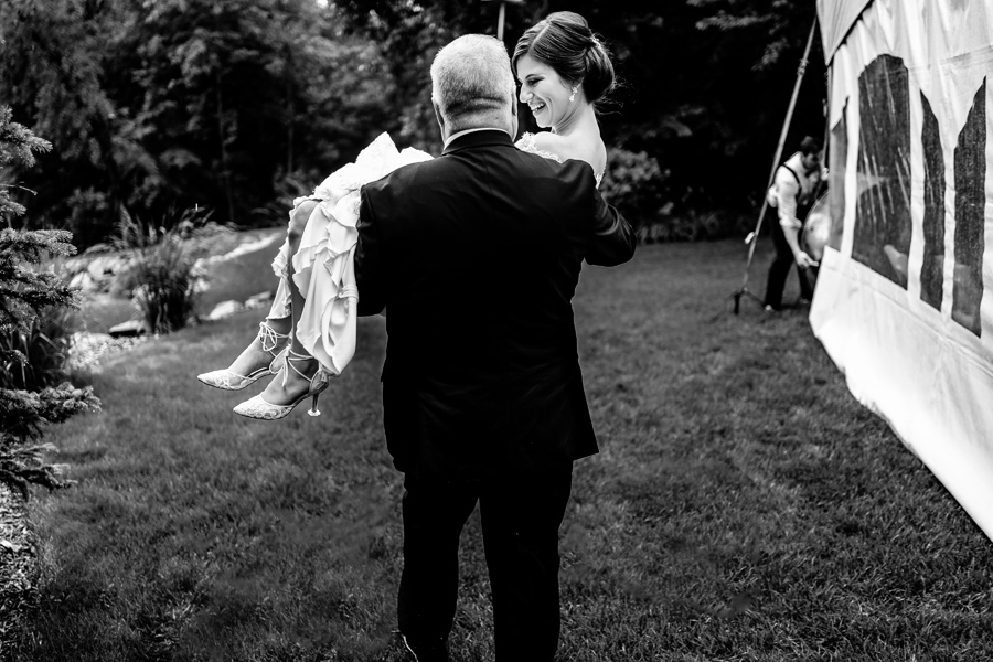 A black and white photo of a bride being carried by her father.