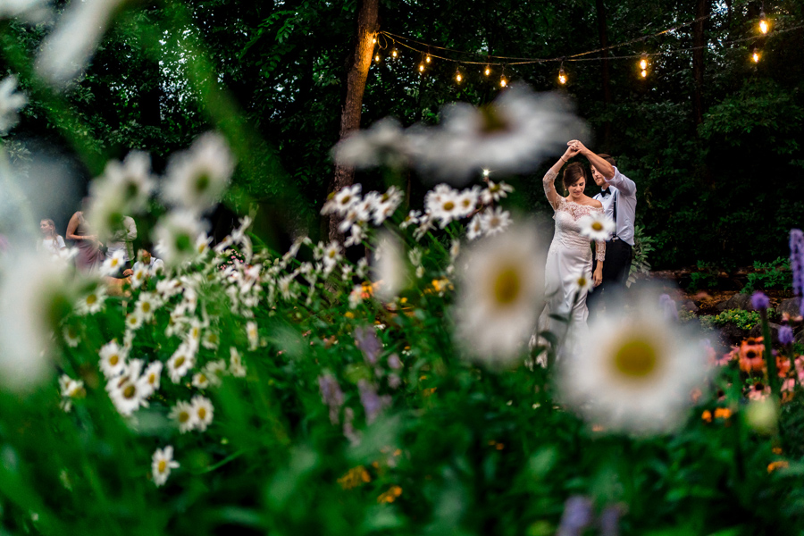 A bride and groom dancing in a field of daisies.