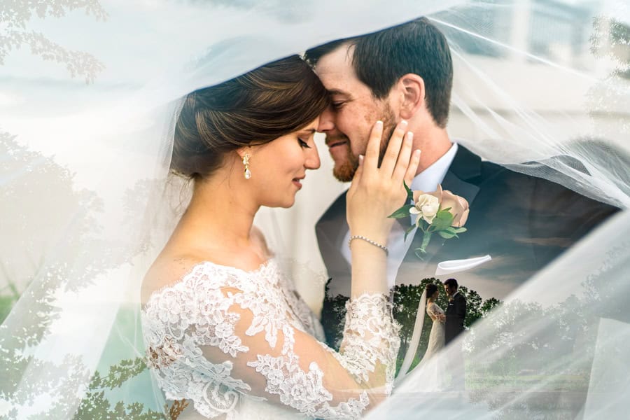 A bride and groom kissing under a veil.