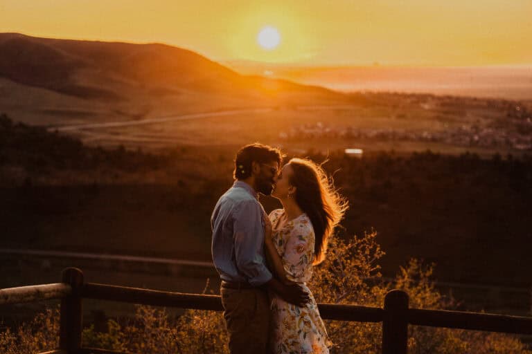 A couple kisses at sunset during their engagement session, captured for the Ultimate Wedding Planning Guide.