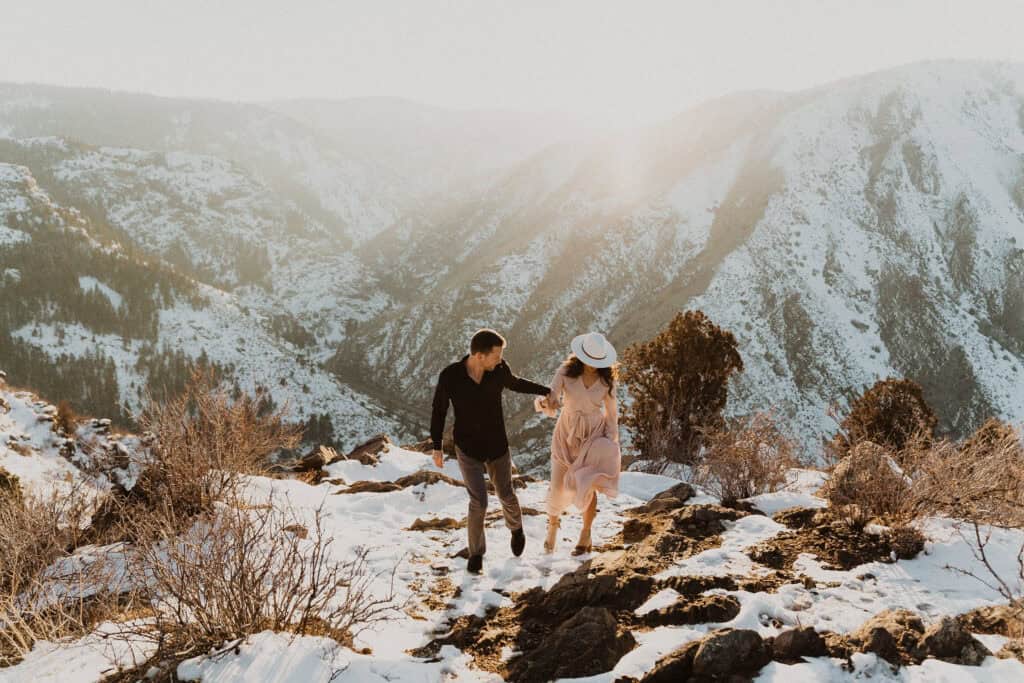 A couple walking down a mountain during their engagement session, captured in the Ultimate Wedding Planning Guide.