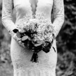Black and white photo of a bride holding a bouquet at Courtney and James’ Love-Filled Backyard Trempleau Wedding.