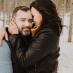 A couple hugging in the snow during their engagement session.