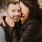 A couple hugging in the woods during their winter engagement session.