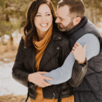 A couple embracing in the snow during their engagement session.