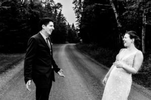 A bride and groom laughing on a dirt road.