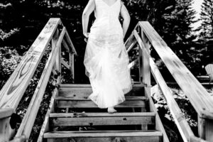 A bride is walking down the stairs in her wedding dress.