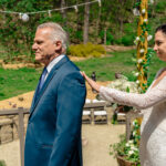 A bride is gently guiding her father's hand on her shoulder at Courtney and James' love-filled backyard Trempleau wedding.