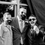Three men with beards and sunglasses posing for a photo at an emotional backyard wedding in La Crosse.