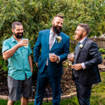 Three groomsmen with beards standing in an emotional backyard wedding.