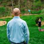 A Love-Filled backyard Trempleau wedding featuring a game of cornhole in the grass.