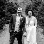 A love-filled backyard Trempleau wedding captured in a black and white photo of a bride and groom walking down a path.
