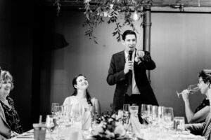 A man is giving a speech at a dinner table.