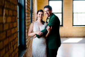 A bride and groom posing in front of a brick wall.