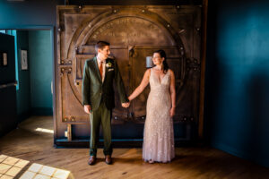 A bride and groom standing in front of a large door.