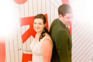 A bride and groom posing in front of a sign.