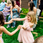A little girl is dancing with a group of people at Courtney and James' love-filled backyard party.