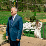 A love-filled man in a suit standing on a wooden deck at Courtney and James' backyard wedding.