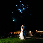 A bride and groom share an emotional kiss in front of fireworks at their backyard wedding in La Crosse.