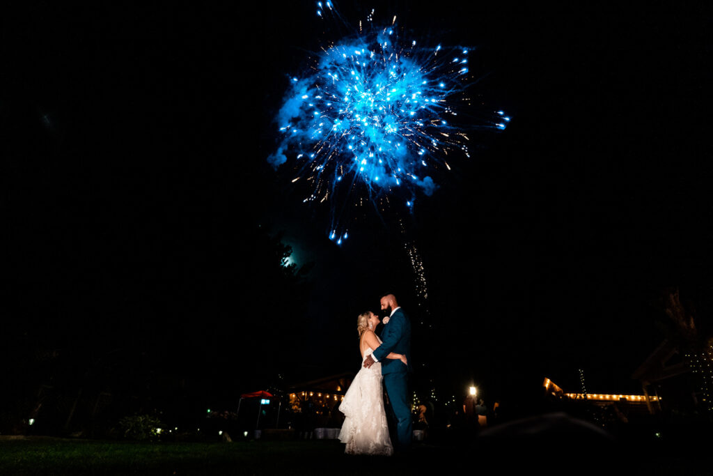 An emotional bride and groom at an intimate backyard wedding in La Crosse, standing in front of a blue firework.