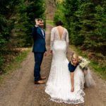 A bride and groom in love standing on a dirt road in the woods at Courtney and James' backyard wedding.