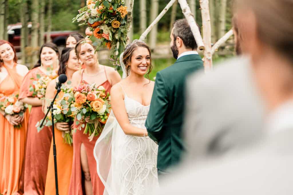 A bride and groom smile at each other during their wedding ceremony.