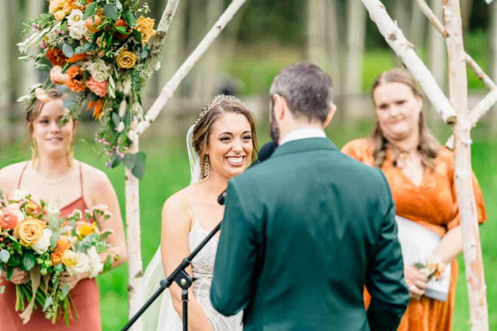A bride and groom smile at each other during their wedding ceremony.