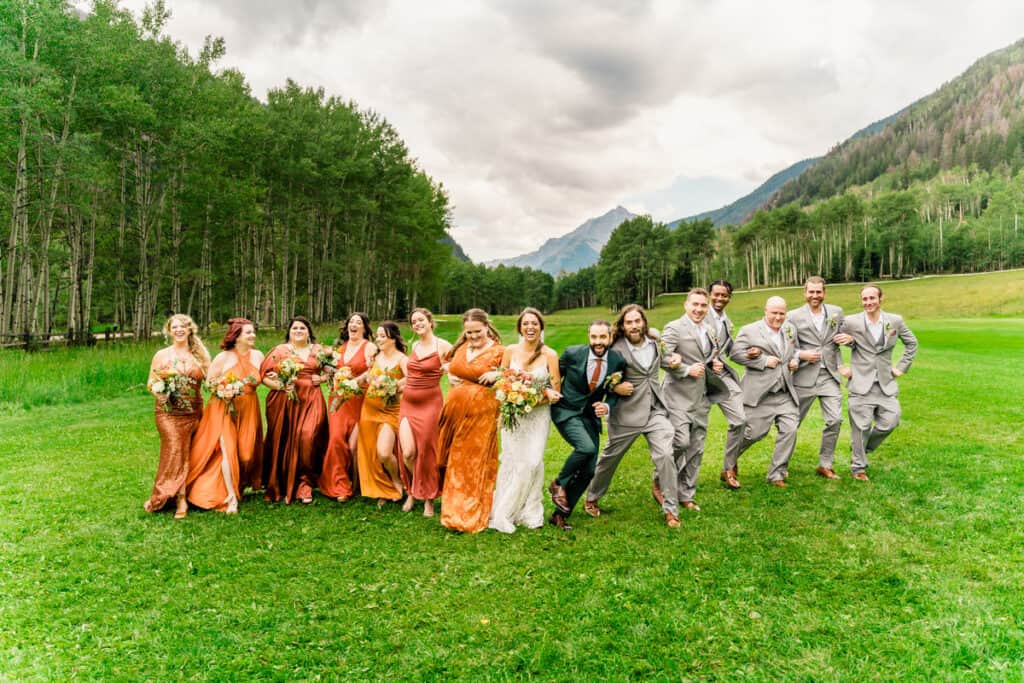 A group of bridesmaids and groomsmen in orange dresses.