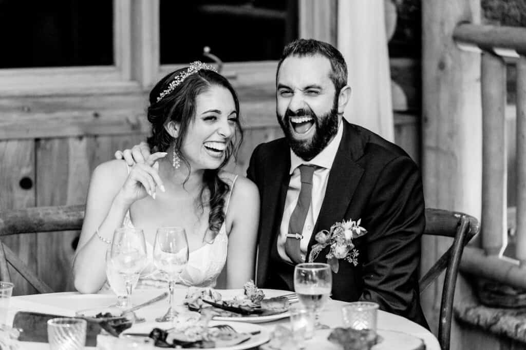 A black and white photo of a bride and groom sitting at a table.