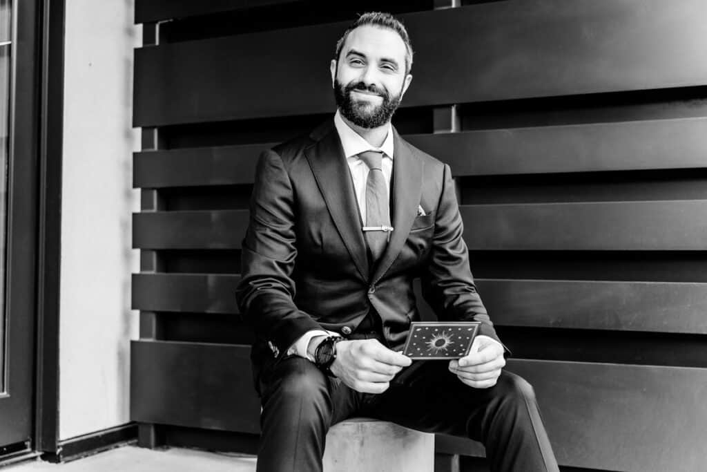 A black and white photo of a man in a suit sitting on a concrete block.